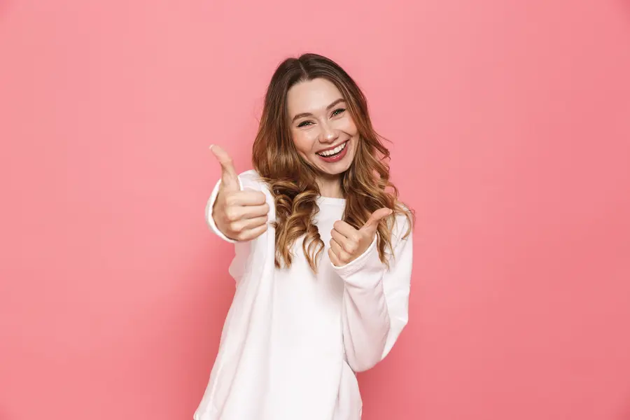Mujer sonriente celebrando con los pulgares hacia arriba