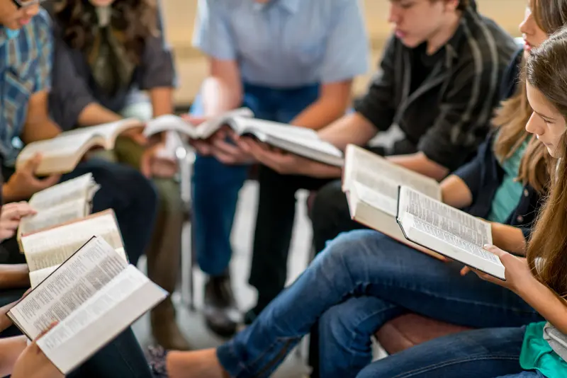 Grupo de jóvenes leyendo y estudiando juntos